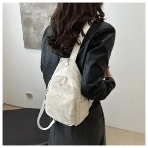 Detail of off-white multi-pocket chest bag with natural crinkle texture on a model
