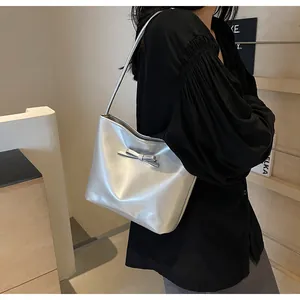 Chic silver bucket bag with bow detail worn by a model in a minimalist setting
