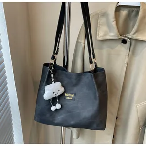 Detail of black matte tote bag with gold brand logo and cute white cloud charm