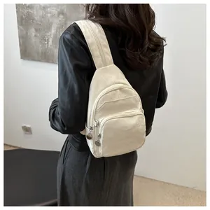 Detail view of off-white nylon crossbody bag with silver hardware on model