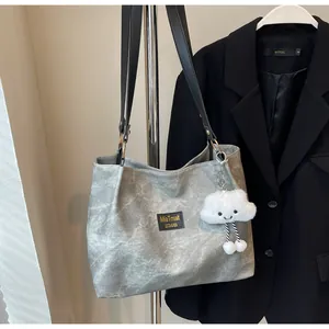 Detail of grey minimalist tote bag with MiaTmait logo and plush cloud charm accessory