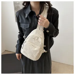 Detail view of multi-zipper sporty crossbody chest bag in cream white nylon
