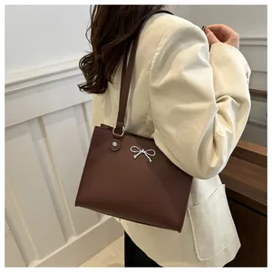 Detailed view of brown tote bag with silver bow ornament on corduroy blazer