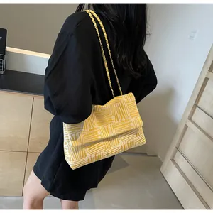 Detail of yellow woven texture crossbody bag with elegant chain strap on shoulder