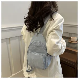 Detail of light blue nylon crossbody bag with multi-zipper compartments on model