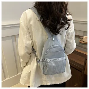Close-up of light blue wrinkled fabric chest bag on person in minimalist interior