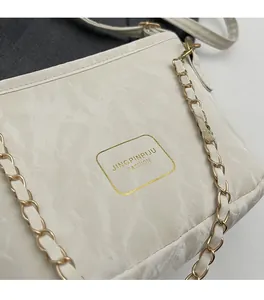 Gros plan détaillé d'un sac bandoulière blanc effet marbre avec chaîne dorée élégante