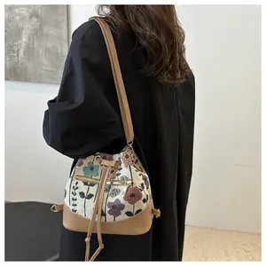 Detail view of floral jacquard bucket bag with khaki leather trim on a model