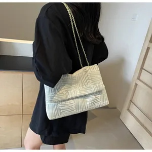 Detail view of large capacity crossbody bag with woven texture and gold chain strap