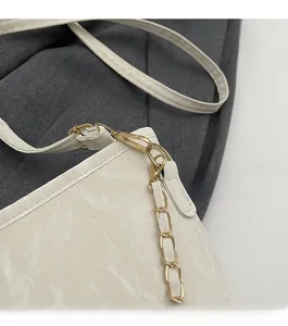 Détail d'un sac à main blanc texturé marbre avec boucle dorée et bandoulière chaîne