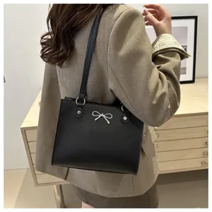 Close-up of black leather tote bag with silver metal bow detail and round strap rings