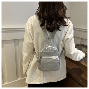 Detail of silver metallic mini backpack showing pleated texture and sleek zippers