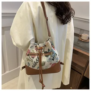 Detail of floral tapestry bucket bag with brown leather trim and front zipper pocket