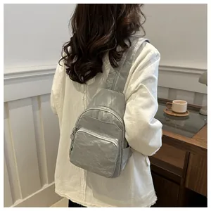Close-up of metallic silver pleated backpack with multiple zippers on model back