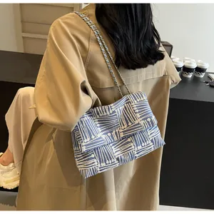 Detail view of a blue and white geometric woven crossbody bag with metal chain strap