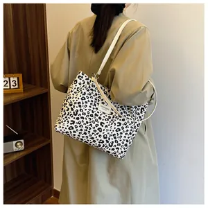Detail of leopard print canvas tote bag with leather strap and decorative woven label