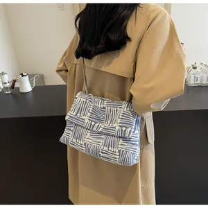 Detail of blue and white geometric woven crossbody bag with metal chain strap