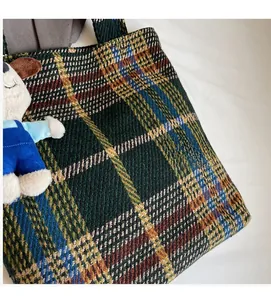 Detailaufnahme der grünen Karo-Tragetasche mit Tweed-Struktur und Plüsch-Hundeanhänger