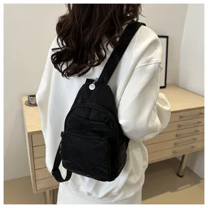 Detailed view of a black pleated nylon crossbody bag with multi-zipper compartments