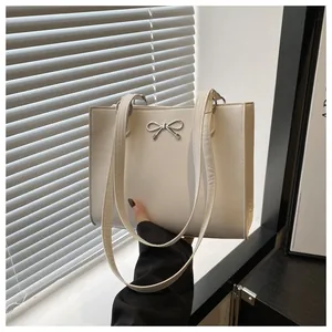 Detail of white tote bag featuring a silver bow buckle and accordion side gusset