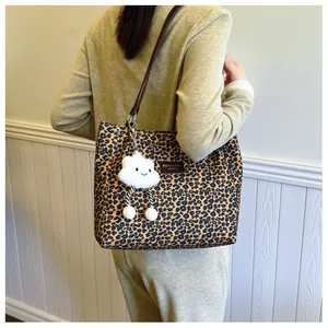Detail of leopard print tote bag with white cloud charm and long brown shoulder strap
