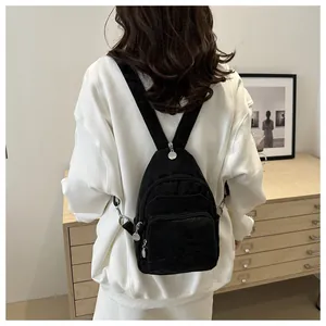 Detail of a black mini nylon backpack showing front zip pockets and silver metal zippers