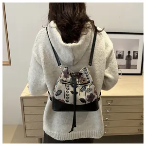 Detail view of a floral tapestry bucket backpack with black base on a female model