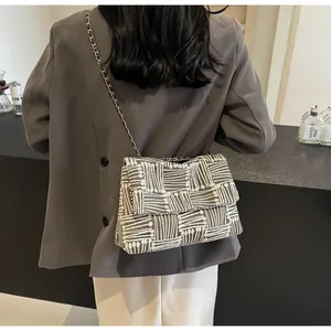 Detail of geometric pattern crossbody bag with metal chain strap on a grey blazer outfit