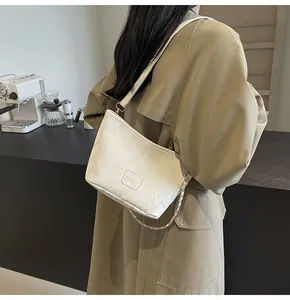 Mannequin portant un sac seau crème à texture marbrée et bandoulière chaîne dorée