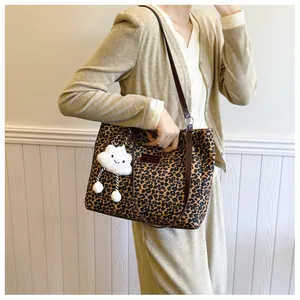 Detail view of leopard print tote bag with cute cloud plush charm on a shoulder strap