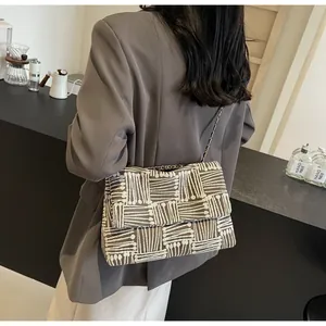 Detail of grey geometric woven crossbody bag with silver chain strap on model