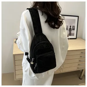 Detail of black sporty crossbody bag with wrinkled nylon texture and zip compartments
