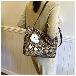 Detail of leopard print tote bag with brown leather straps and plush cloud charm