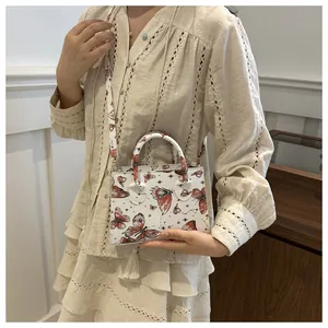 Detailed view of white butterfly crossbody bag with artistic prints on model
