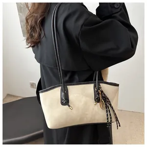 Dettaglio borsa shopper beige in pelle scamosciata con finiture nere e ciondolo tennis