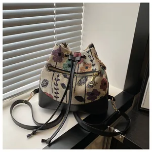 Detailed macro view of vintage floral jacquard fabric and black leather bucket bag base