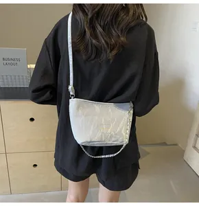 Gros plan d'un sac seau gris clair plissé avec chaîne porté par un mannequin