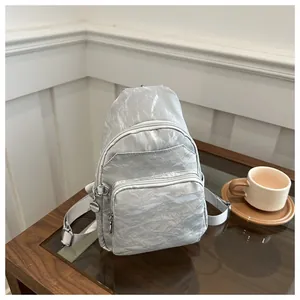 Detail of silver metallic textured crossbody chest bag with adjustable strap and zippers