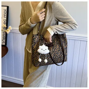 Detail shot of leopard print tote bag with cute cloud charm and brown leather straps