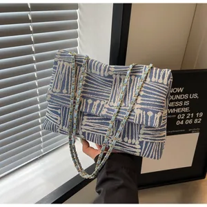 Detail of blue and white geometric woven fabric with gold metal chain strap on bag