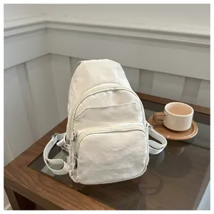 Detail of off-white multi-pocket nylon chest bag with wrinkled texture on wooden table
