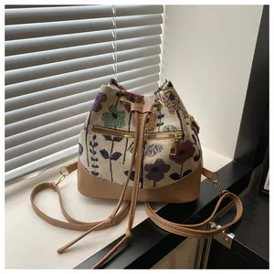 Detailed view of floral jacquard bucket bag with drawstring and brown leather trim