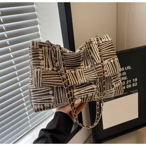 Close-up of jacquard fabric texture and gold chain strap on the geometric shoulder bag
