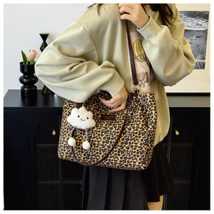 Detail of leopard print tote bag with thin leather straps and white plush cloud charm