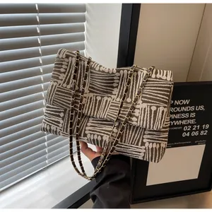 Close-up of woven chain strap and brown geometric pattern on a flap shoulder bag