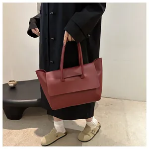 Close-up of matte wine red leather tote bag with unique flap detail and lychee texture