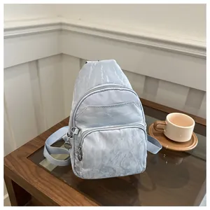 Close-up of light blue crossbody chest bag with wrinkled marble texture on wood table