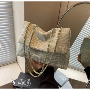 Detail of light green jacquard crossbody bag with abstract textures and chain strap