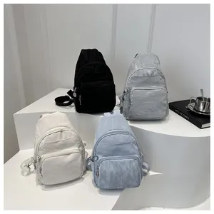 Detail view of colorful nylon chest bags with pleated texture on white geometric stands
