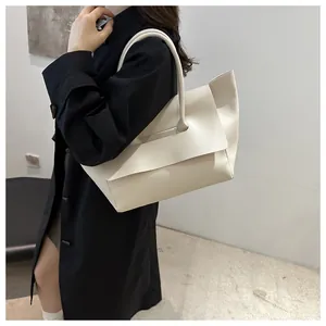 Detailed side view of cream leather tote bag paired with a black trench coat for work